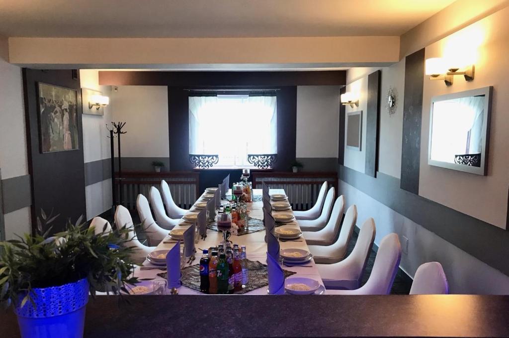 a long table in a room with white chairs at Noclegi Hexe in Żegocina