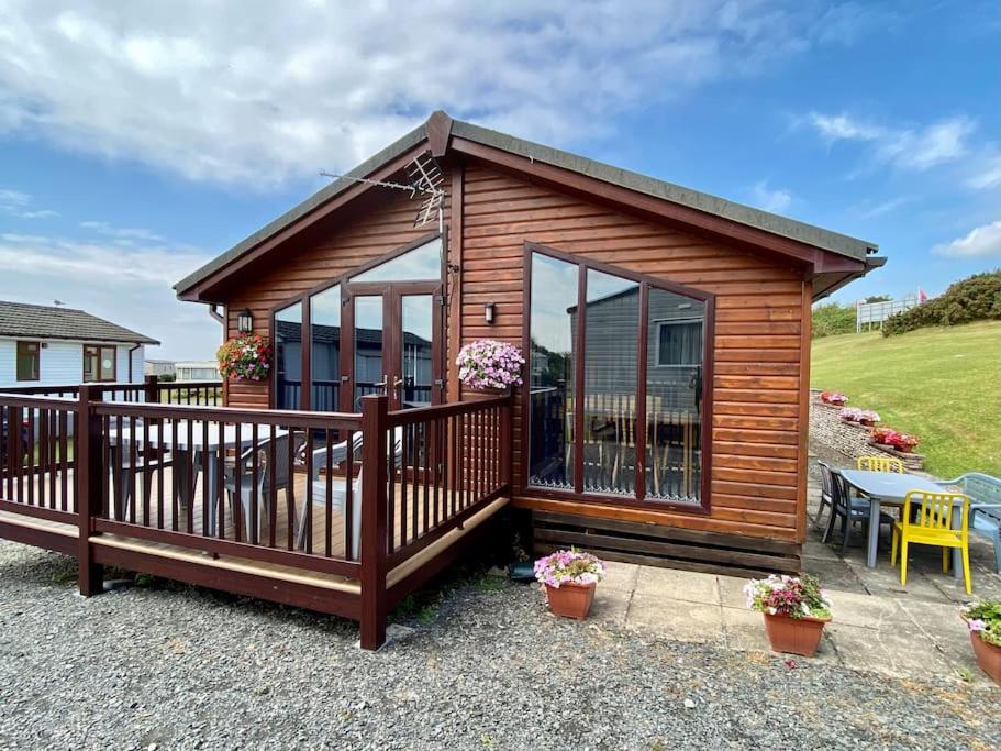 a wooden cabin with a deck and a patio at Lake View Lodge in Millom