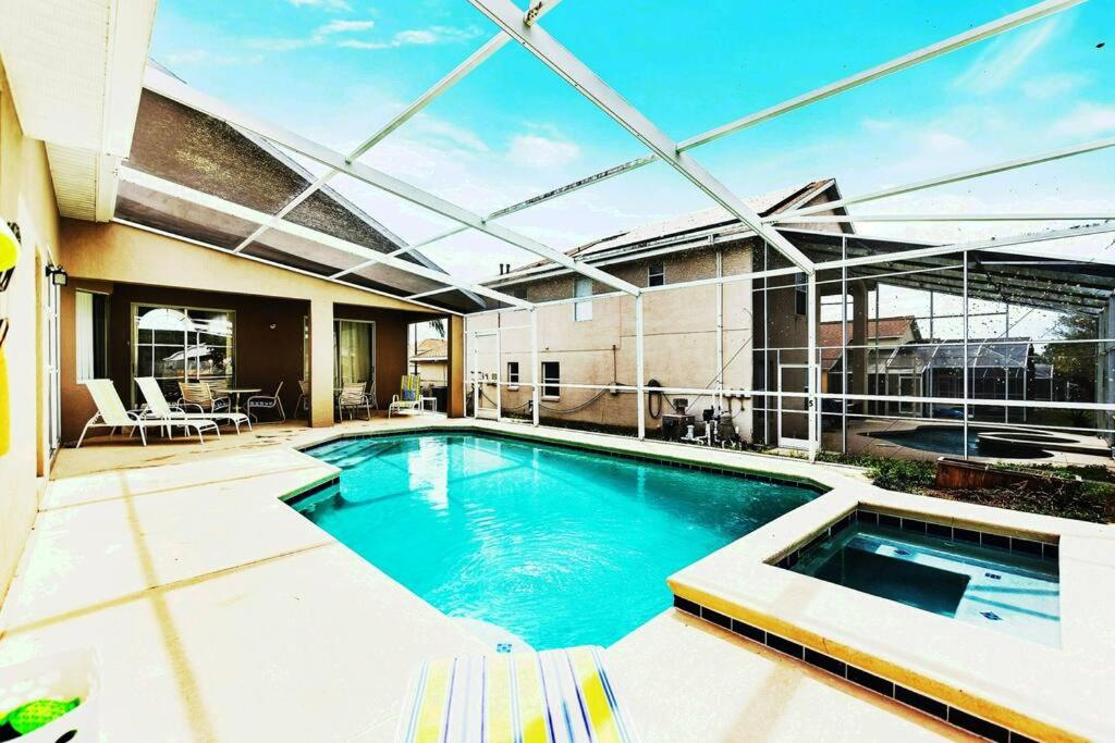 basen z patio i budynek w obiekcie Spacious Disney Themed 5Bed Villa! Private Heated Enclosed Pool/Spa/BBQ! w mieście Davenport