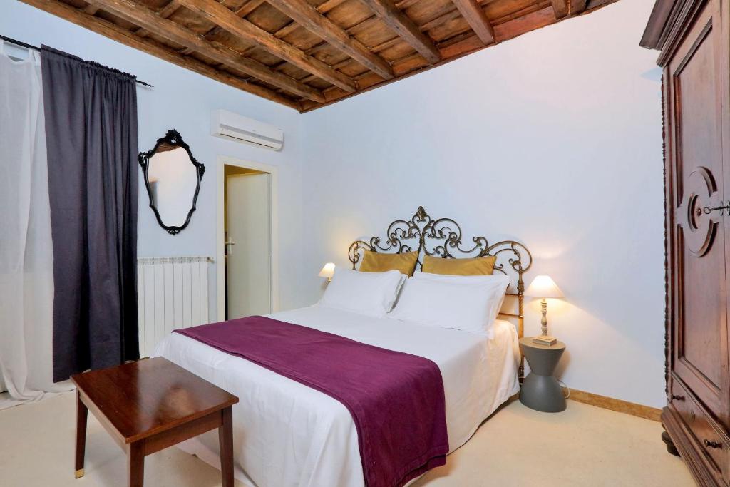 a bedroom with a large white bed and a wooden ceiling at Residenze Romanae - Sangallo Rooms in Rome