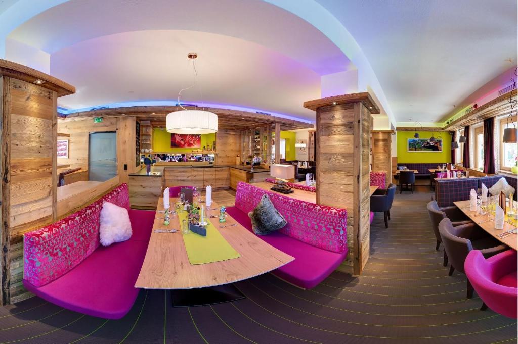 un restaurante con mesas y sillas rosas en una habitación en Hotel Toni, en Galtür