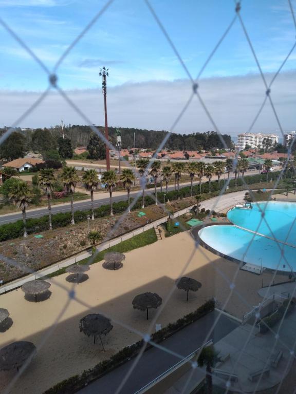 a view through a fence of a patio with umbrellas at Vista Marina Laguna Vista Algarrobo in Algarrobo