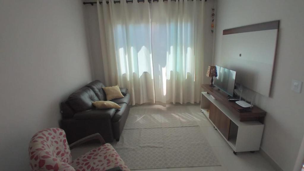 Casa aconchegante com piscina e bem localizada في فوز دو إيغواسو: غرفة معيشة بها أريكة وتلفزيون