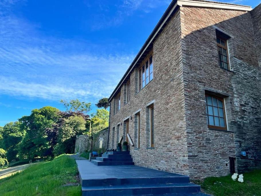 a brick building with stairs leading up to it at Fledgling Barn: stunning new coastal holiday home in Kingsbridge