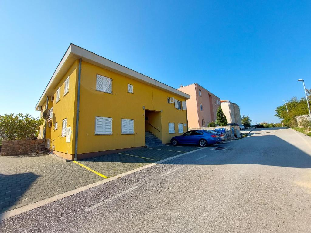 un edificio giallo con un'auto parcheggiata in un parcheggio di Apartment Niko a Klenovica
