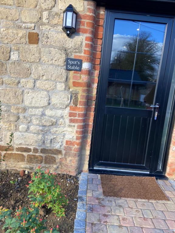 una porta nera sul lato di un edificio di mattoni di Potcote farm stables accommodation spots stable a Towcester