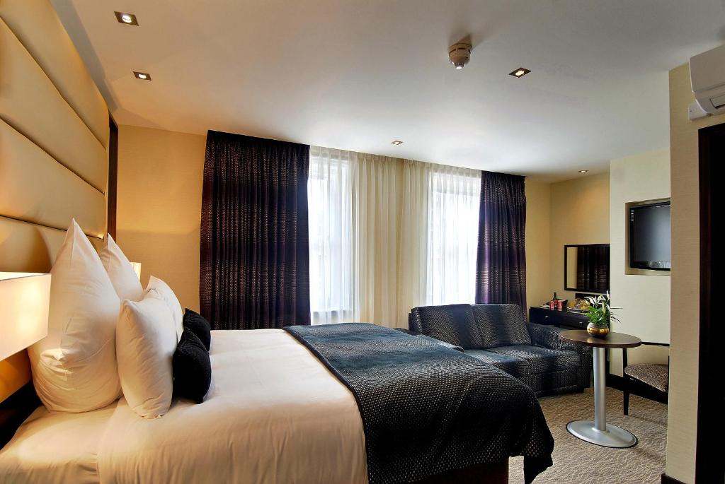 ロンドンにあるMontcalm Marble Arch Townhouseのベッドとソファ付きのホテルルーム