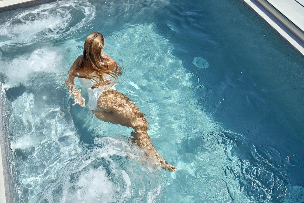 GrandeMar Suites في مدينة أستيباليا: امرأة تسبح في الماء في المسبح