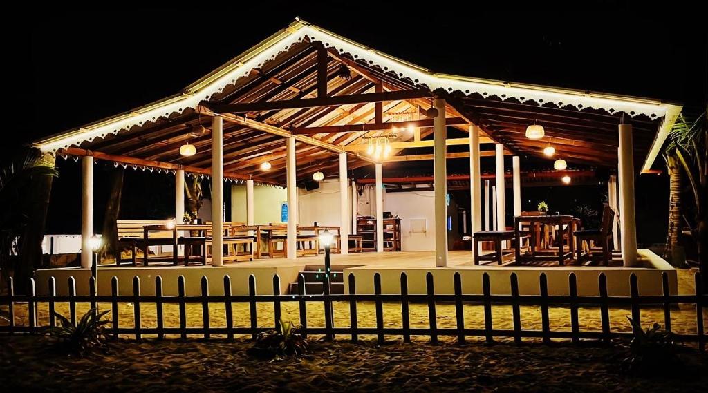 un pabellón de madera con mesas y sillas por la noche en Vibes and Tides Beach Resort by Enlightened Vagabond en Gokarna