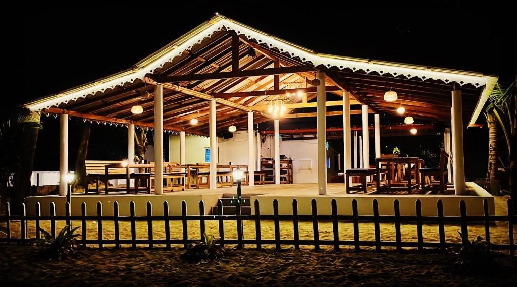 a wooden pavilion with tables and chairs at night at Vibes and Tides Beach Resort by Enlightened Vagabond in Gokarna