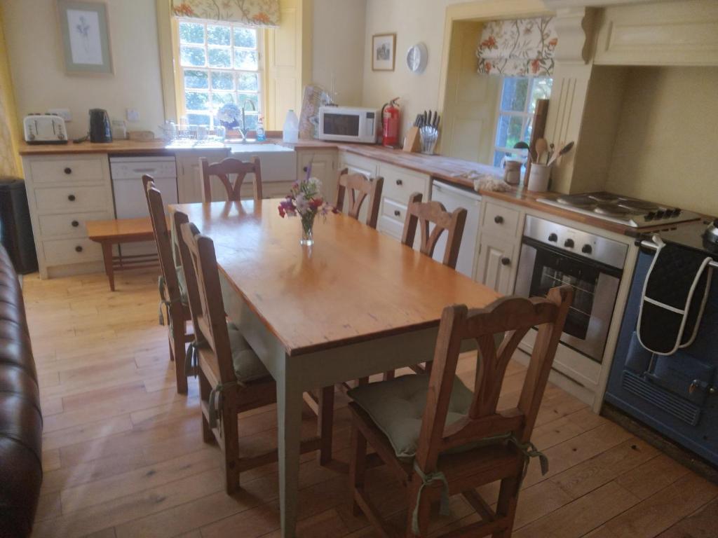 cocina con mesa de madera con sillas y horno en Forget Me Not Holiday Cottage en Dalmellington