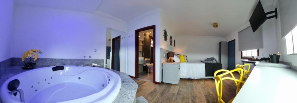 a large bathroom with a tub and a bedroom at Biz & Biu Pousada Lavras Novas in Lavras Novas