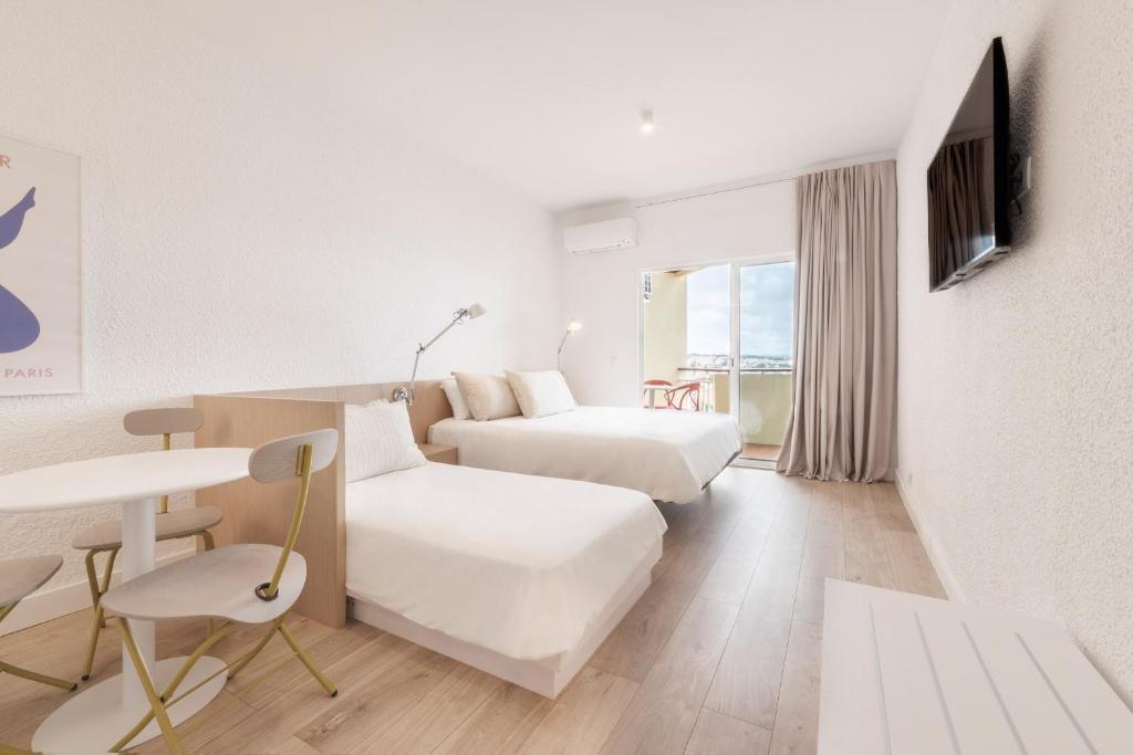 カスカイスにあるEquador Superior Suites by Olala Homesのベッド2台とテーブルが備わるホテルルームです。
