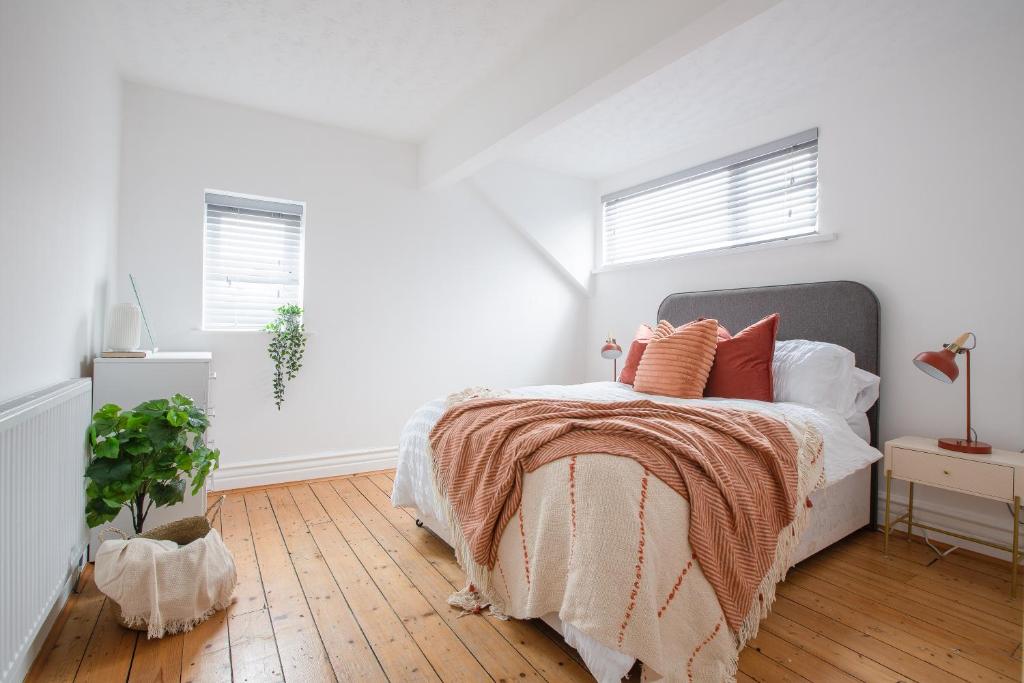 a white bedroom with a bed with orange pillows at Charles Alexander Short Stay - Hove Suite in Lytham St Annes