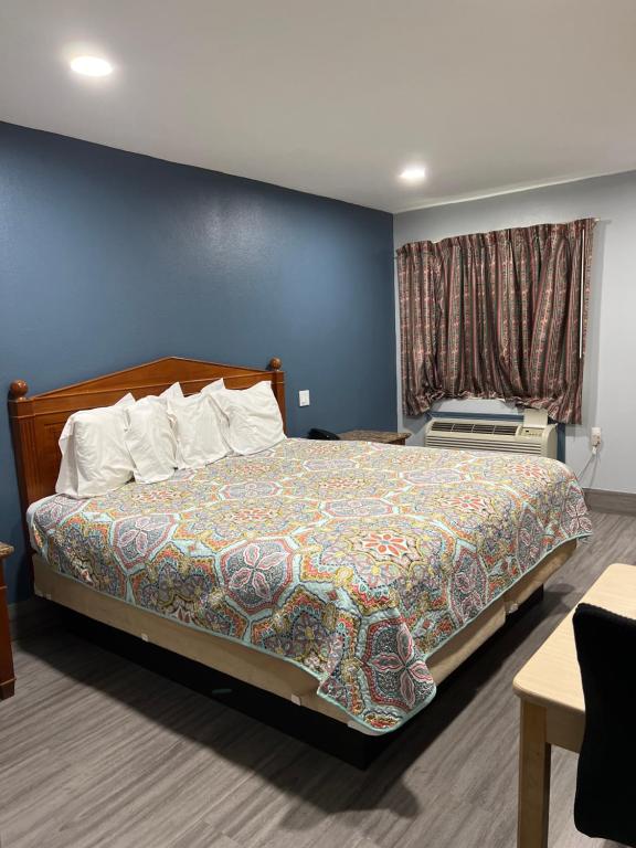 1 dormitorio con cama y pared azul en Budget Inn en Hallettsville