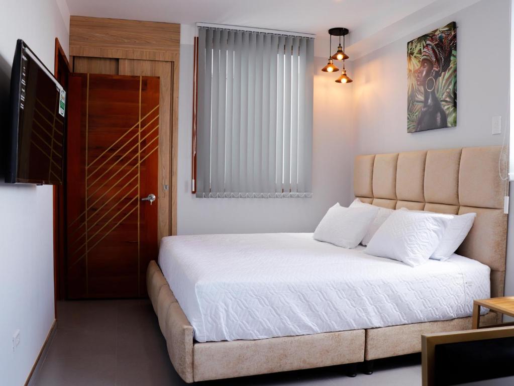 a bedroom with a bed with white sheets and a door at HOTEL GOLDEN CARTAGO in Cartago