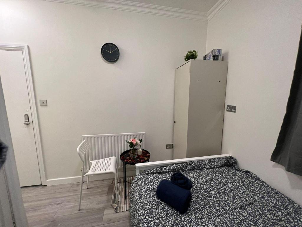 a bedroom with a bed and a clock on a wall at Lovely apartment close to Acton central station in London