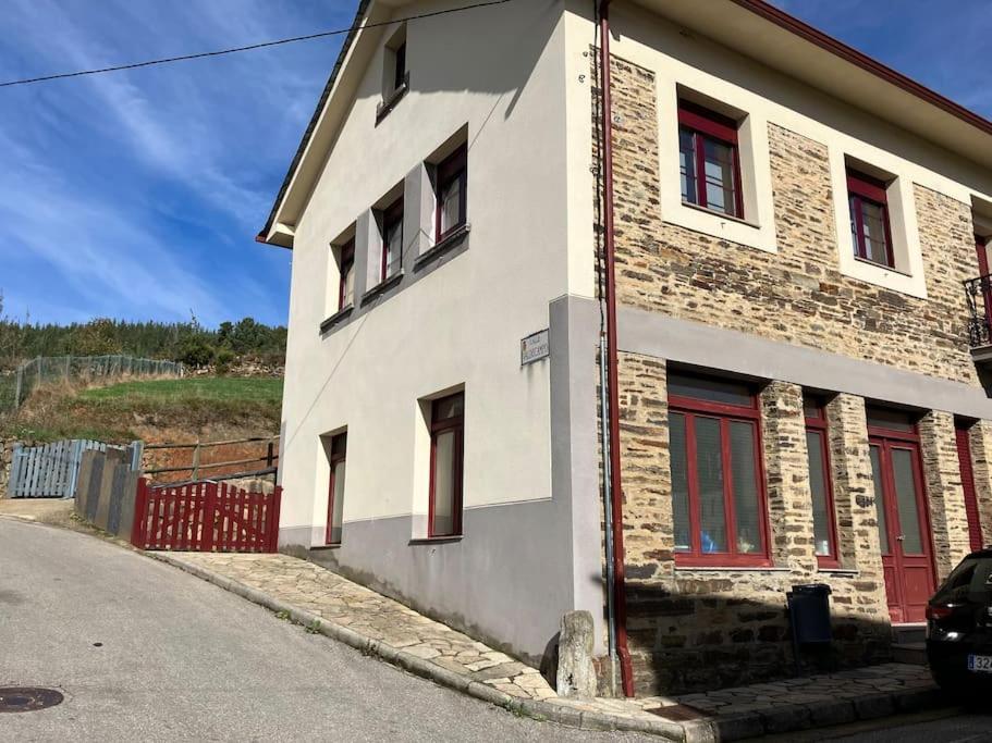 un edificio blanco con ventanas rojas en una calle en A Casa da Fonte, en Santa Eulalia de Oscos