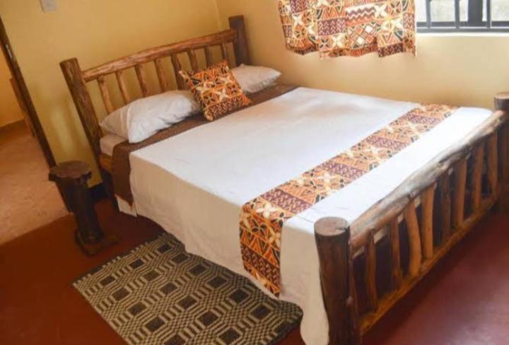 a bedroom with a large wooden bed in a room at Hillsgate Hotel in Namanga