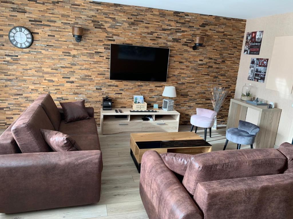- un salon avec deux canapés et un mur en briques dans l'établissement Au cœur de Lisieux 83 m2 et vue sur la Basilique, à Lisieux