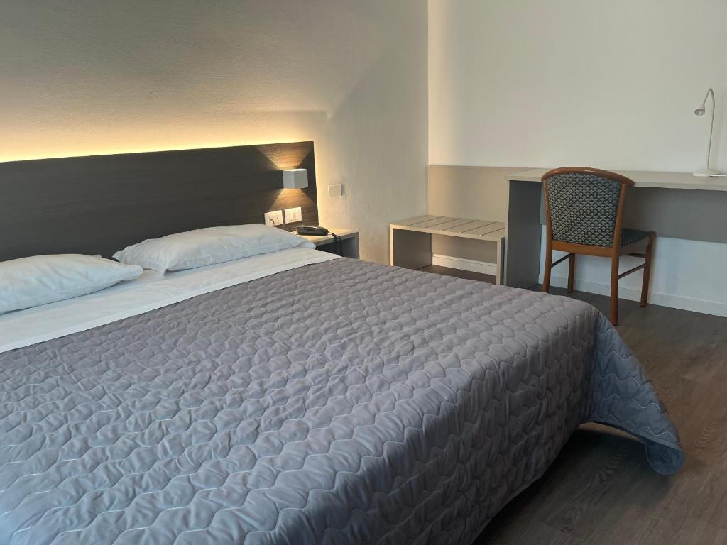 a bedroom with a large bed and a chair at Hotel Friuli in Cervignano del Friuli