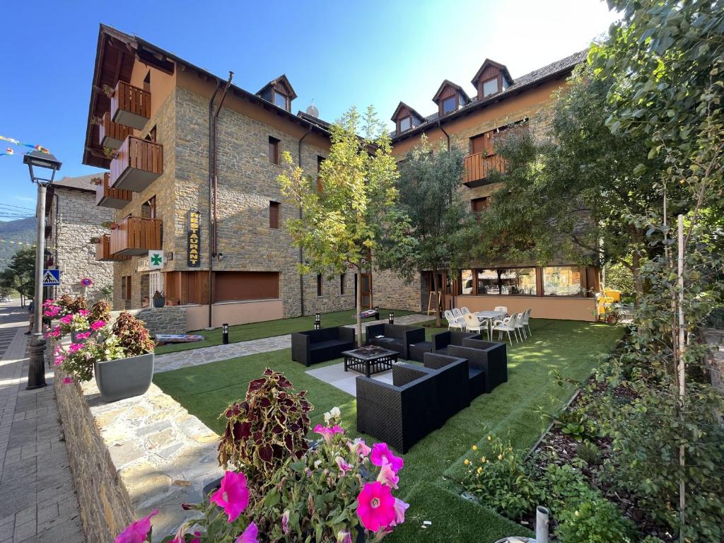 a courtyard of a building with black furniture and flowers at Hotel Els Encantats in Espot