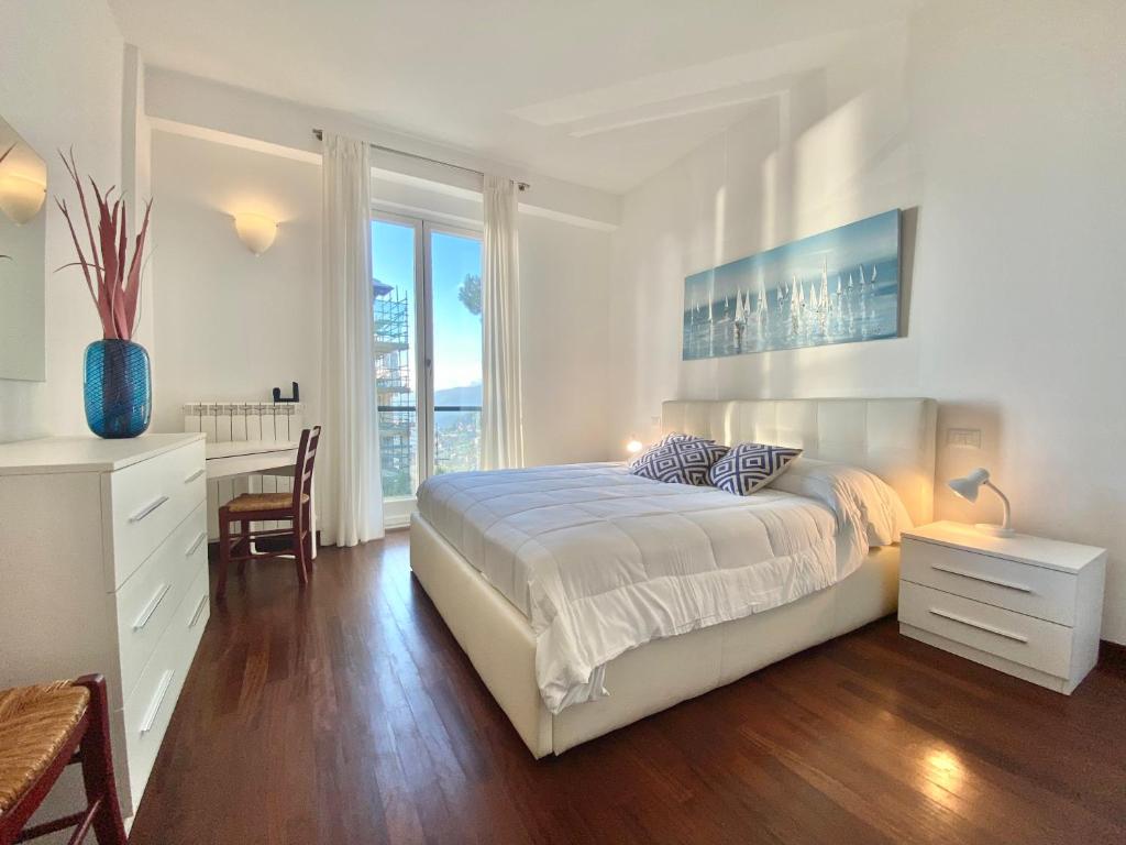 een witte slaapkamer met een bed, een bureau en een raam bij CASAVIVA - Bilo with SeaView and parking in Camogli in Camogli
