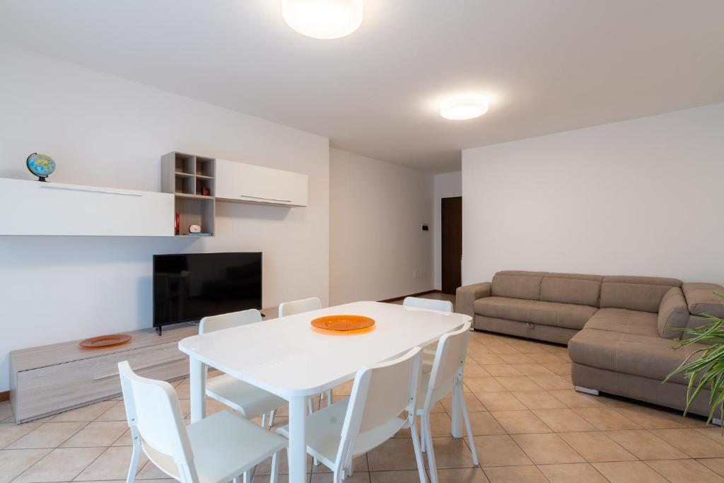 un soggiorno con tavolo e sedie bianchi e un divano di MIZAR- Appartamento privato con parcheggio gratuito by Appartamenti Petrucci a Foligno