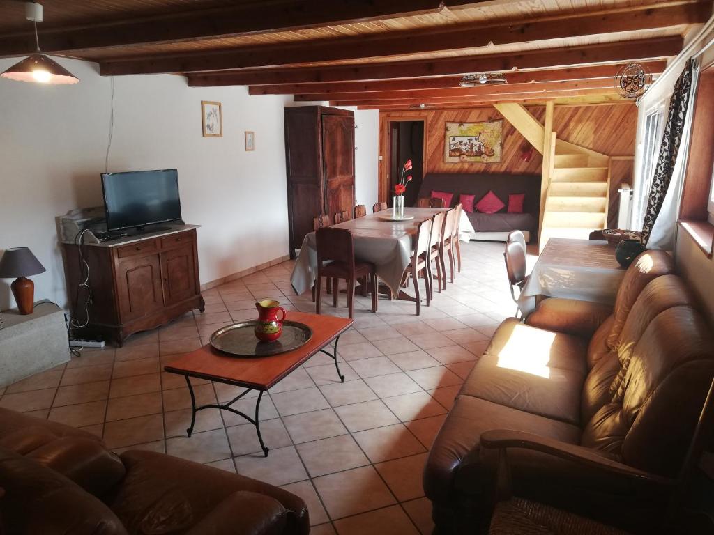 a living room with a table and a dining room at Grand gite 14 personnes ,cour ,salle de jeux, proche du village , commerces in Murat