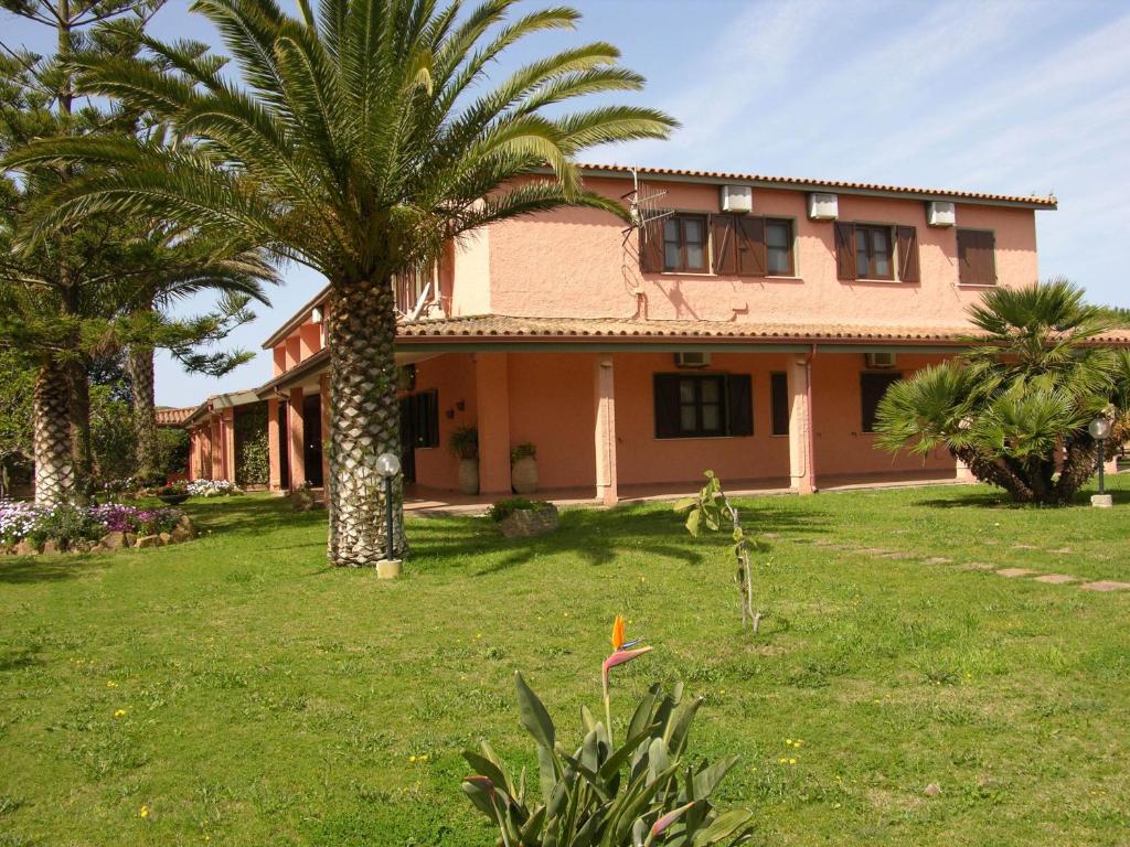 a house with a palm tree in the yard at Hotel Su Giudeu in Chia