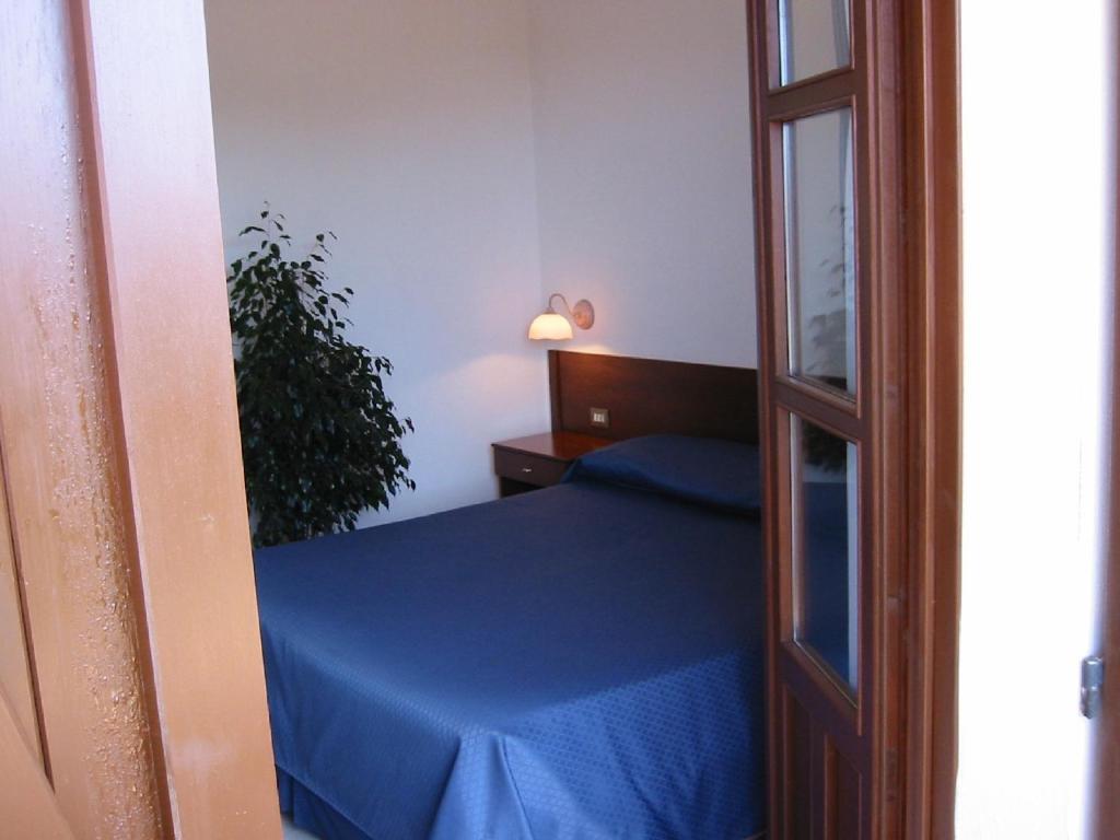 a bedroom with a blue bed and a glass door at Hotel Su Giudeu in Chia