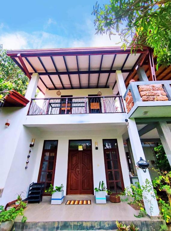 a house with a wooden door and a balcony at Sanuki Villa in Hikkaduwa
