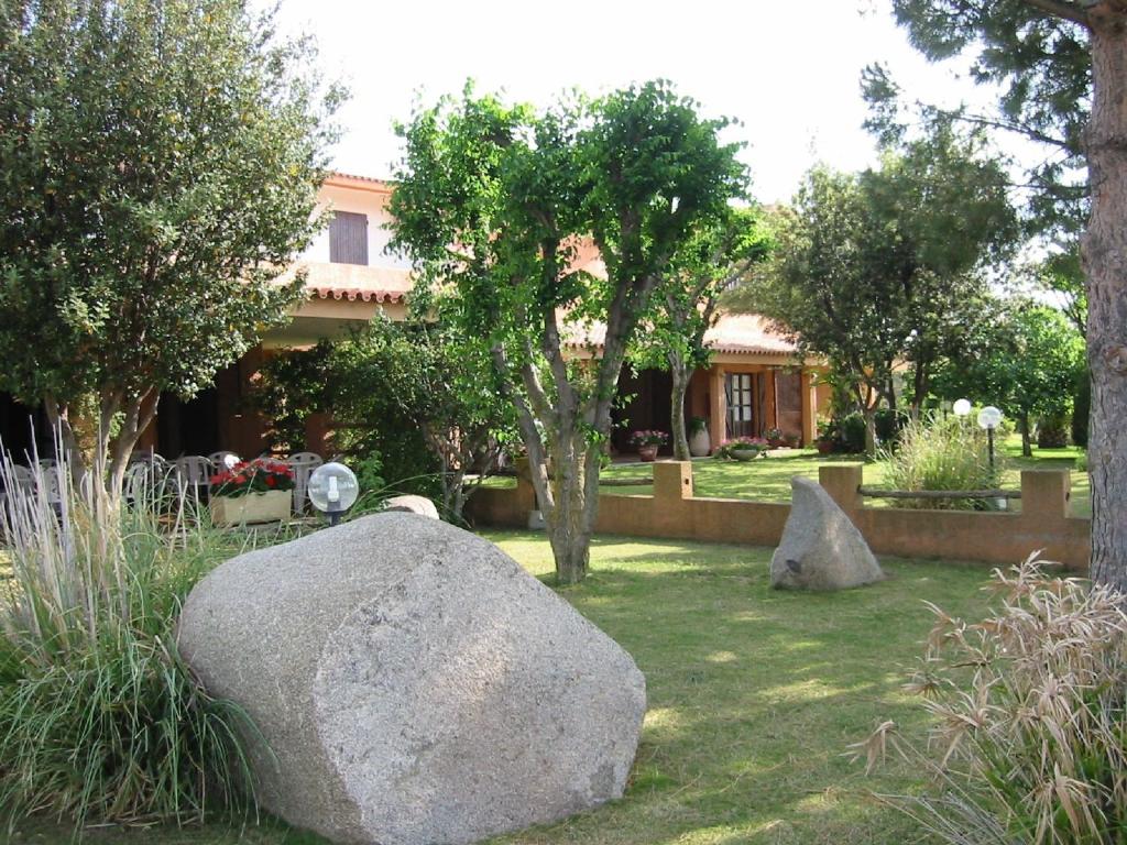a garden with a large rock in front of a house at Hotel Su Giudeu in Chia