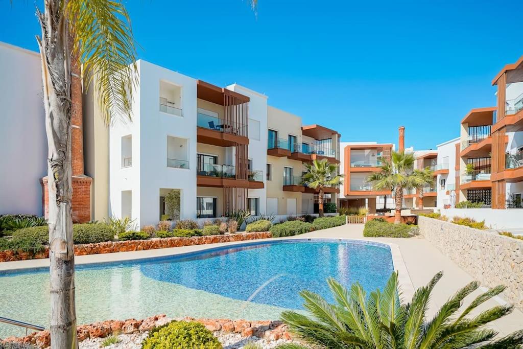 a villa with a swimming pool and palm trees at Terraços do Rio by CORAL in Portimão