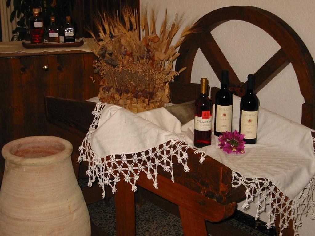 a table with bottles of wine and a vase at Hotel Su Giudeu in Chia