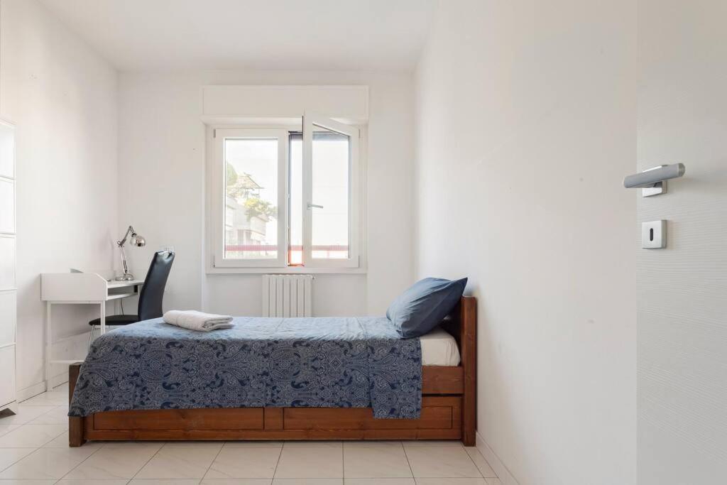 1 dormitorio con cama, escritorio y ventana en Attico incantevole - Forum Assago & Humanitas, en Rozzano