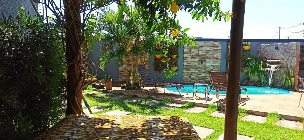 um quintal com uma piscina com um banco e árvores em Pousada Casa Bom Sono em Foz do Iguaçu
