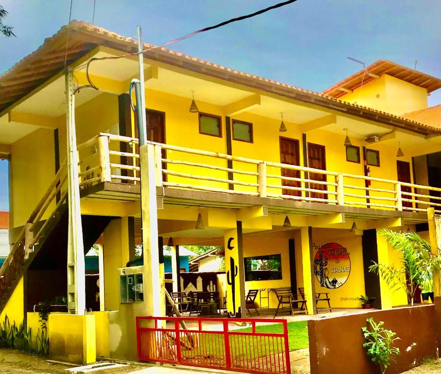 a yellow house with a porch and a balcony at Pousada Cordel de Itaúnas in Itaúnas