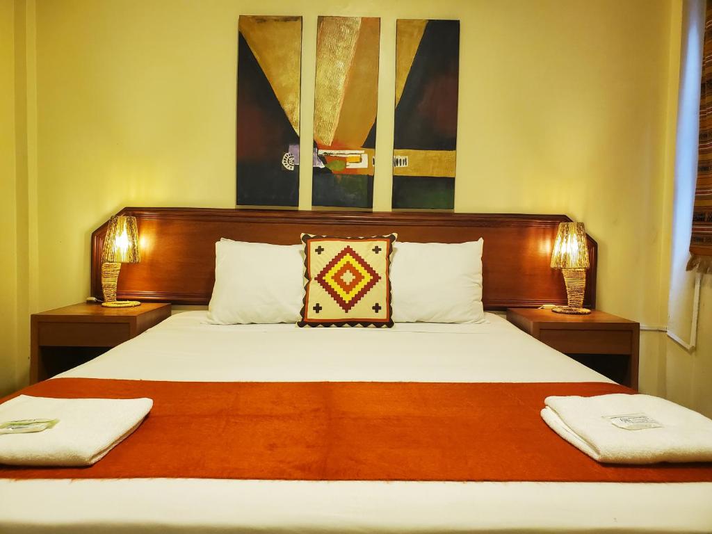 um quarto com uma cama grande e 2 candeeiros em Dreamkapture Hostel close to the airport and bus terminal em Guayaquil