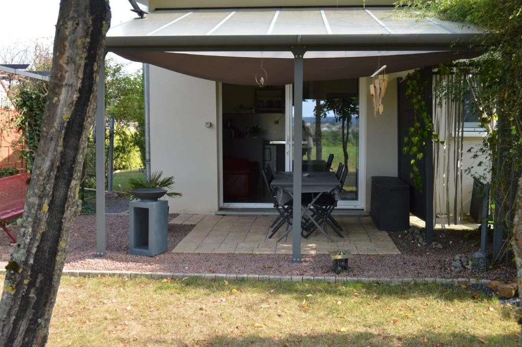 a patio with an umbrella and a table at meublé entier indépendant en contigu de ma maison in Saint-Georges-sur-Moulon