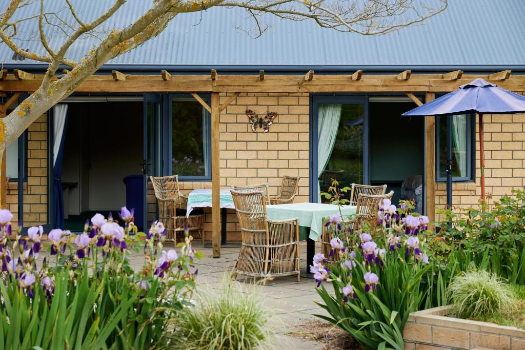 um pátio com uma mesa, cadeiras e flores em Awatea Country Bed & Breakfast em Kaikoura