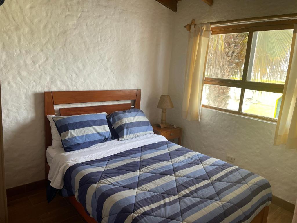 Un dormitorio con una cama azul y blanca y una ventana en Departamento pequeño 2 BR en zona ideal de Paracas, en Paracas