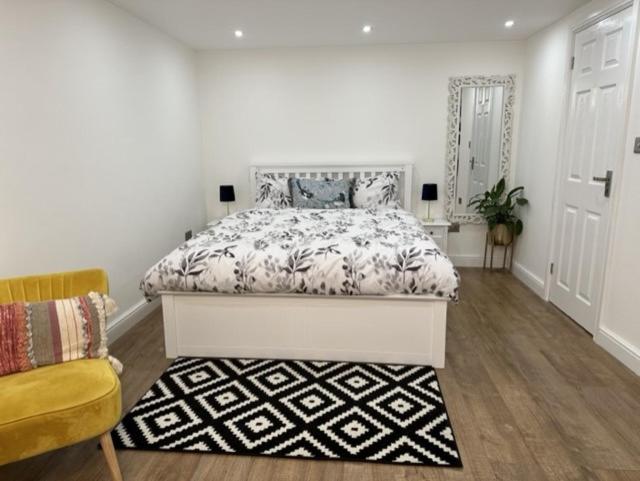 a white bedroom with a bed and a rug at Touchwood in Isleworth
