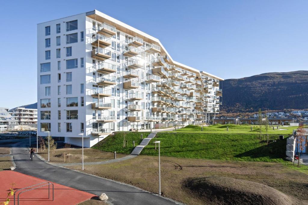 um grande edifício de apartamentos branco com uma colina ao fundo em Royal Skir apartment sea view em Tromsø