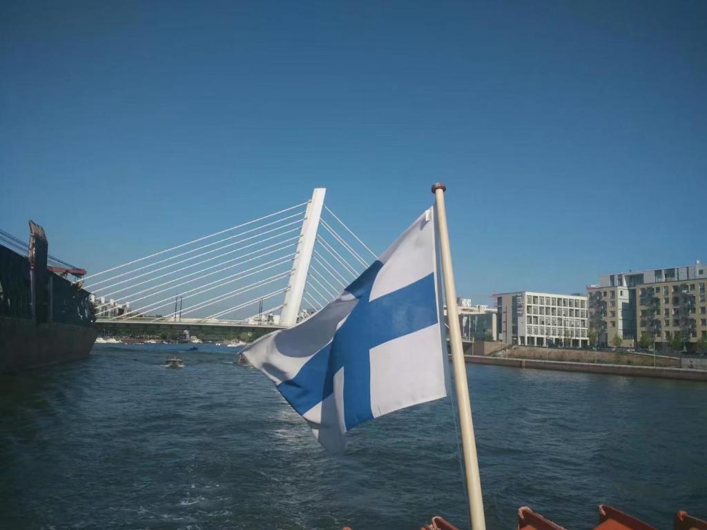 a flag on a pole next to a river with a bridge at Helsinki Penthouse near the west harbor in Helsinki