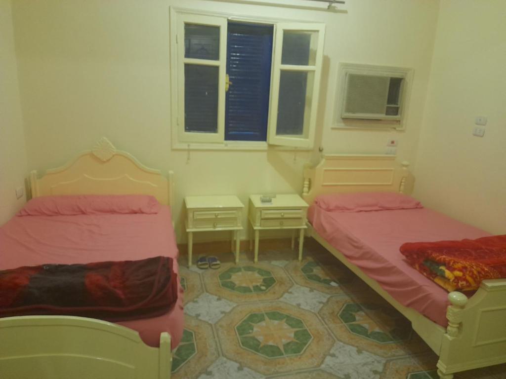 a room with two beds and two windows at Grand house in Nag` el-Ramla