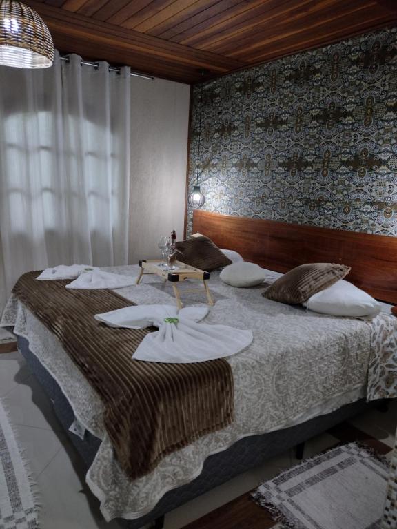 ein Schlafzimmer mit einem großen Bett mit weißen Platten darauf in der Unterkunft Chale Disco de Arado in Visconde De Maua