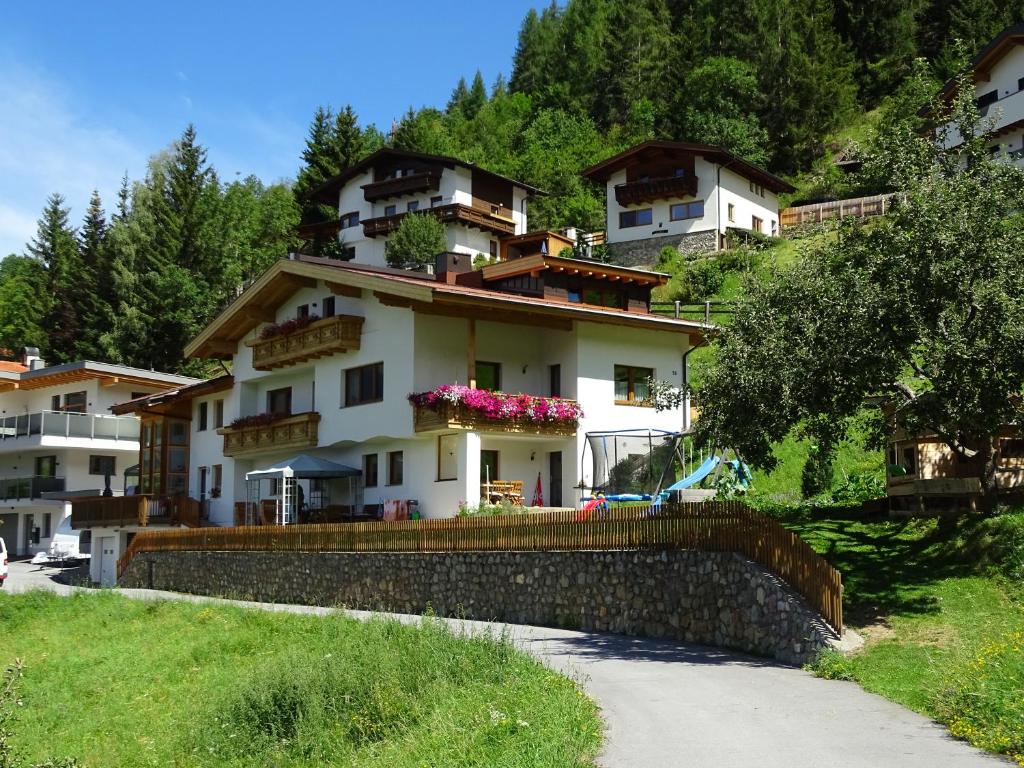 una casa en la cima de una colina con una pared de piedra en Haus Anita, en Fendels