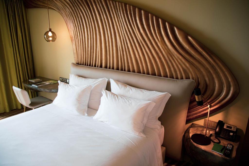 a bedroom with a bed with white pillows at Vila Foz Hotel & SPA - member of Design Hotels in Porto