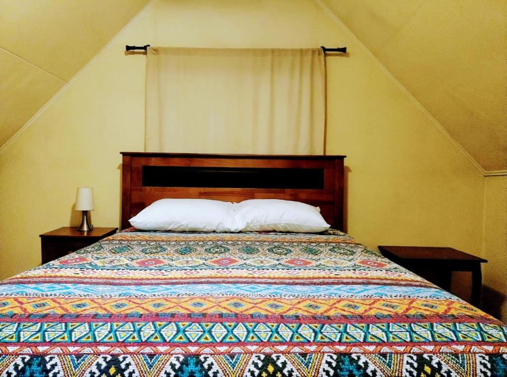 1 dormitorio con 1 cama con edredón y 2 almohadas en Cabañas altos de Mirasol, en Puerto Montt